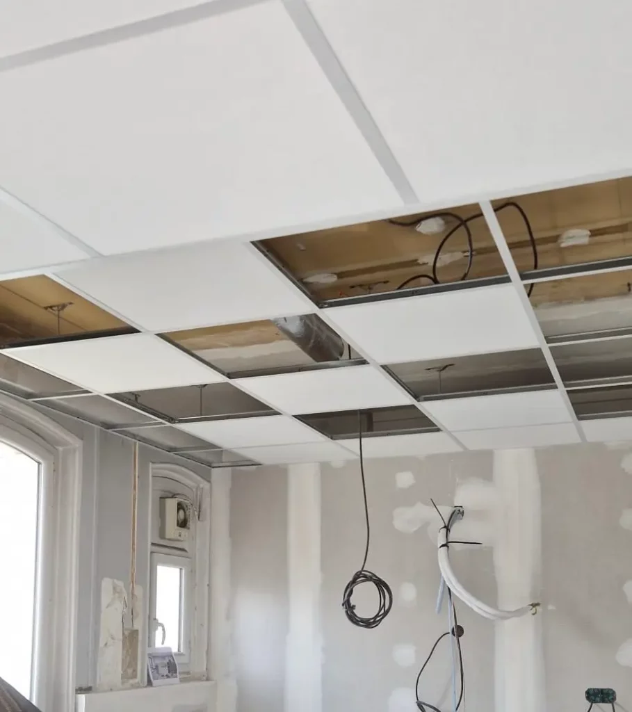 Projets d’aménagement et de réaménagement tertiaire : installation de plafond suspendu. Pose de panneaux de plafond blancs sur structure métallique avec câblage électrique apparent