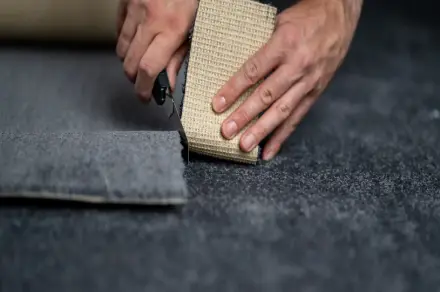 Agencement de bureaux en Île-de-France : poseur coupant une dalle de moquette au cutter avec précision